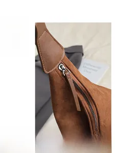 Detail view of smooth metal zipper and leather puller on brown suede shoulder bag