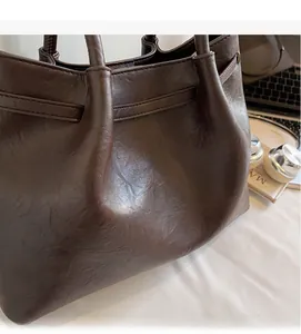 Detail view of large dark brown tote bag with soft pleated texture and long handles