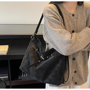 Detail of black large capacity shoulder bag showing soft leather texture and metal buckles