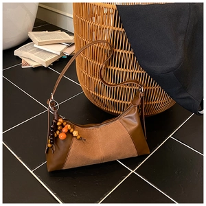 Détail du sac bandoulière vintage marron en patchwork avec texture suède et breloque en bois
