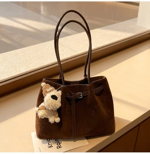 Dettaglio della borsa tote in pelle scamosciata marrone scuro con ciondolo a forma di cane