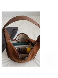 Macro view of brown suede underarm bag interior showing large capacity with daily items