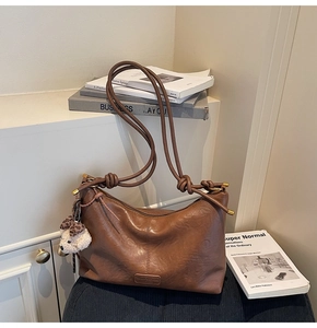 Detail of vintage brown leather handbag with subtle embossed logo and cute bear charm