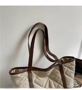 Close-up detail of quilted tote bag featuring reinforced brown handles and cream fabric