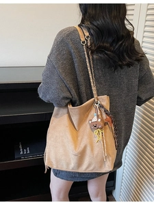 Sac seau en daim beige avec bandoulière chaîne et breloque ours porté par un mannequin