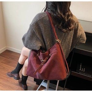 Side view of large burgundy leather tote bag with vintage gold buckle and strap details