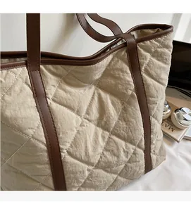 Detail of quilted beige tote bag with brown leather handles and diamond texture pattern