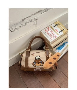 Détail du sac Boston tissé beige avec broderie chiot et breloque baguette