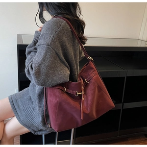 Detail view of burgundy leather tote bag with elegant belt buckle and wide strap
