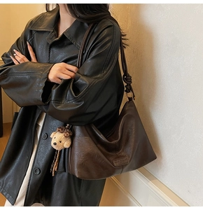 Detail of dark brown hobo bag with a cute teddy bear charm and knotted shoulder strap
