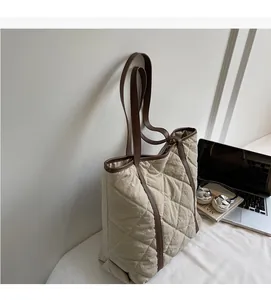 Detail of beige quilted tote bag with brown leather straps and diamond stitch pattern