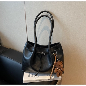 Black pleated leather tote bag featuring a cute brown plush bear charm and long straps