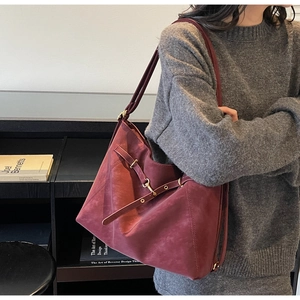 Detail of burgundy vintage tote bag with gold hardware in a bookstore setting