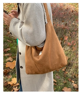Close-up of brown suede tote bag with white faux shearling lining and stylish label detail