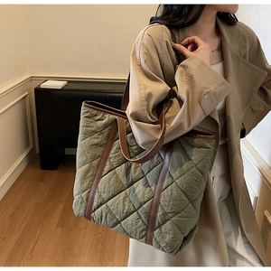 Detail of quilted olive green tote bag with contrasting brown leather handles on shoulder