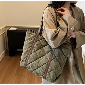 Detail of olive green quilted tote bag with brown leather handles on a trench coat model