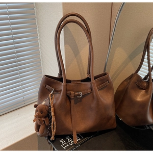 Detail of vintage brown tote bag with leather texture and cute plush bear charm accessory