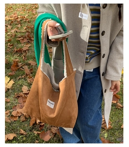 Detail of brown suede tote bag featuring soft white faux shearling lining and logo patch