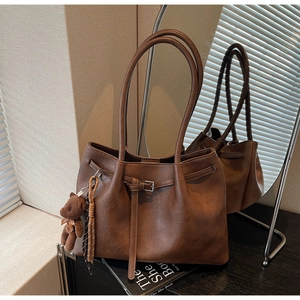 Detailed view of vintage brown pleated tote bag with plush bear charm and buckle