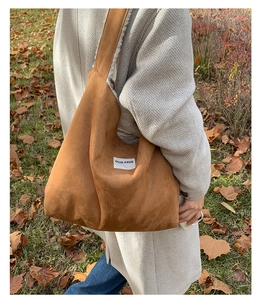 Outdoor shot of large brown suede tote bag with plush lining and white logo patch