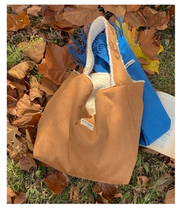 Detail of camel suede tote bag with white faux shearling lining on autumn leaf background