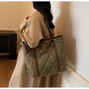 Detail of army green quilted tote bag with brown leather handles worn by a model