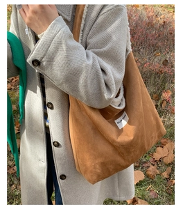 Detail of brown suede tote bag featuring plush faux shearling lining and logo patch