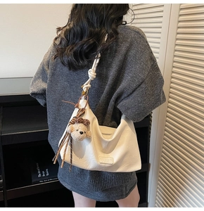 Detailed back view of a white soft leather hobo bag with teddy bear charm on model