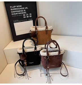 Détail de trois sacs seaux en daim avec bordure en peau de mouton et pompons en fourrure