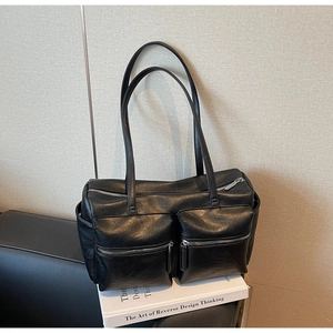 Detailed view of the double front zipper pockets on the black faux leather tote bag