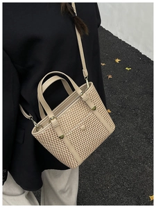Dettaglio borsa tote in paglia intrecciata con finiture in pelle beige e fibbie d'oro