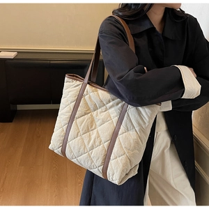 Detailed view of quilted tote bag with brown leather handles and large capacity