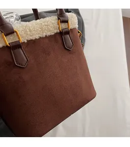 Détail du sac seau en daim marron avec bordure en peau de mouton et boucles dorées