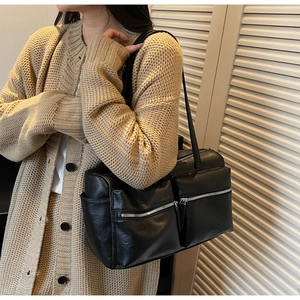 Detail view of large black crossbody bag with silver zippers and multi-pocket design