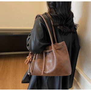 Detail of vintage brown tote bag with decorative buckle and cute bear pendant charm