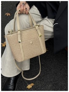 Dettaglio borsa tote vintage in paglia con finiture in pelle e foglie autunnali