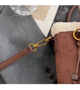 Détail du fermoir mousqueton doré sur sac seau en daim marron avec fausse fourrure