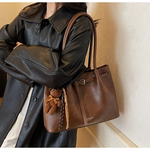 Detail of vintage brown tote bag with leather buckle and cute plush bear charm