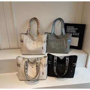Detail view of large canvas tote bags in white, grey and black with woven straps