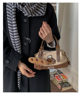 Détail du sac Boston avec broderie Lucky Puppy et charmant accessoire baguette en peluche