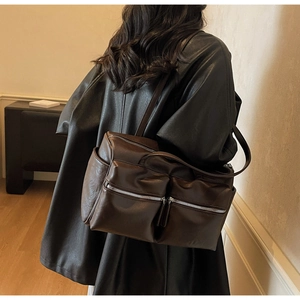 Side view of dark brown large capacity shoulder bag with silver zippers and wide strap