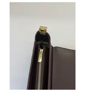 Nahaufnahme von glattem Goldreißverschluss und Beschlägen an dunkelbrauner Ledertasche