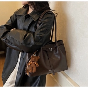 Macro detail of vintage brown tote bag leather texture with plush bear charm accessory