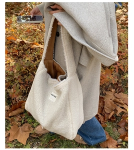 Close-up of a white shearling tote bag with OUR FAVE label in an outdoor autumn setting