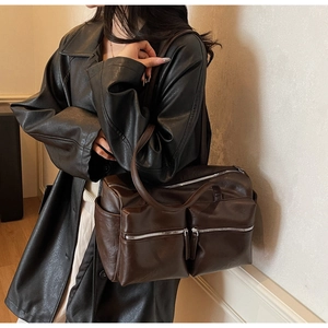 Detail of vintage brown leather shoulder bag with symmetrical front zipper pockets