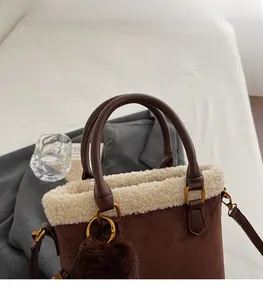 Détail du sac seau en daim marron avec bordure en fausse fourrure blanche et anse en cuir