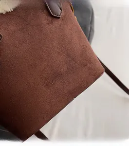 Gros plan sur sac seau en daim marron avec lettrage doré et bordure en polaire