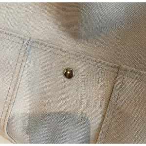Macro shot of durable beige canvas tote bag material with silver metal snap button detail