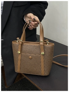 Dettaglio della borsa tote in tessuto marrone con manici in pelle e fibbia dorata