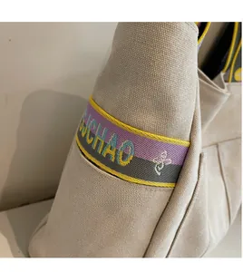 Detail shot of the colorful woven strap with bee motif on the beige canvas tote bag